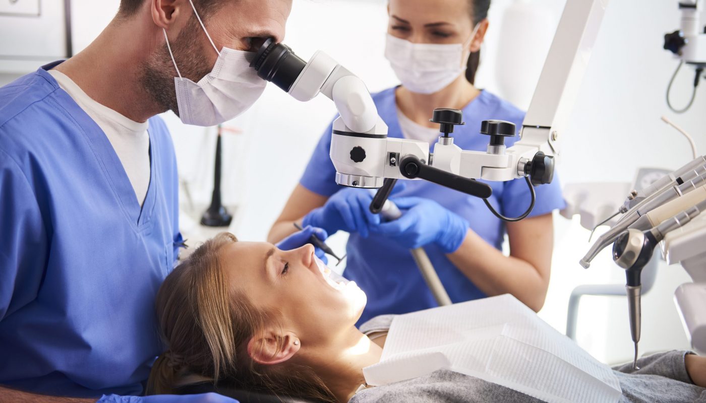 Male dentist working with dental microscope Male dentist working with dental microscope